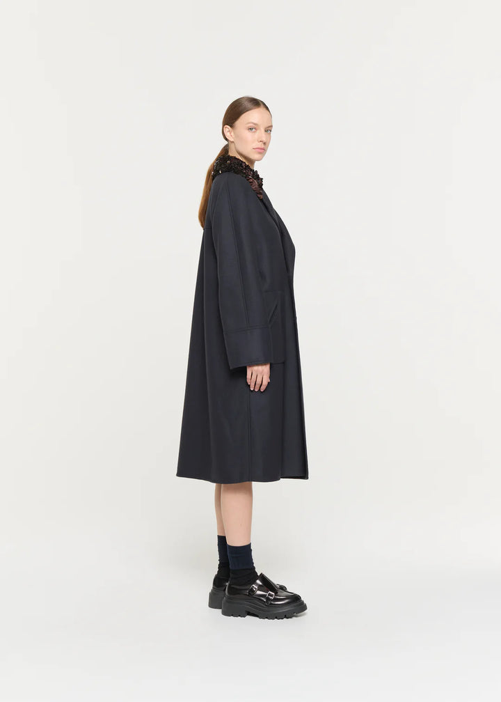 Woman wearing a long dark coat on a white background