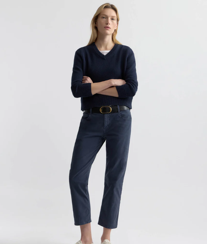 Woman wearing a navy sweater and pants with a white background