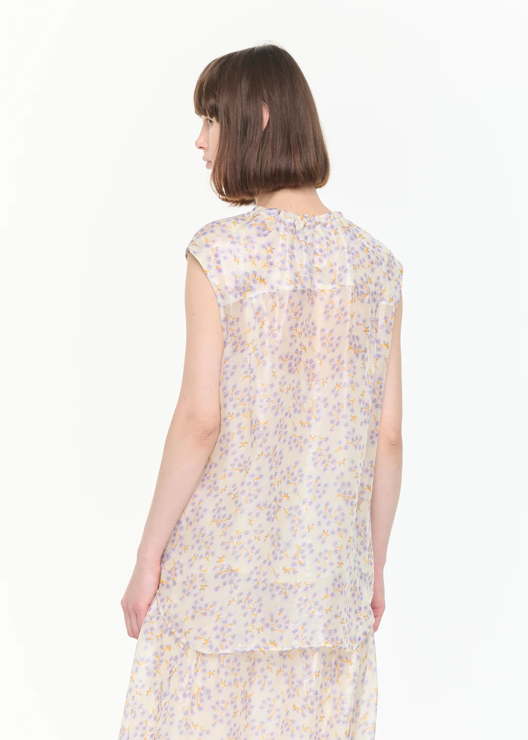 Woman wearing a sleeveless floral dress on a white background