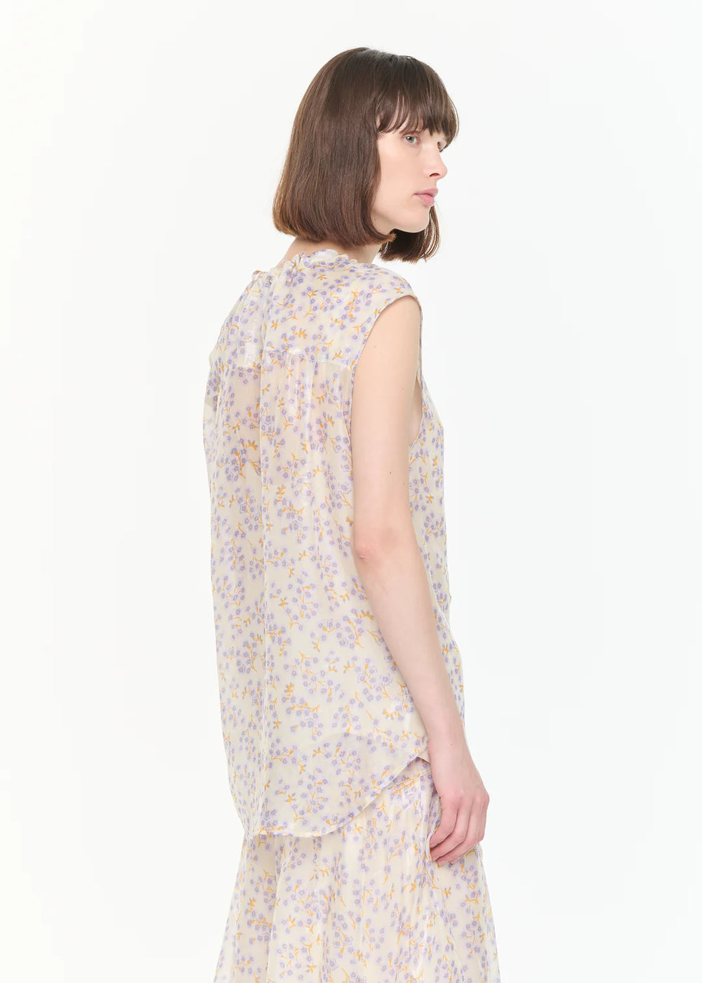 Woman wearing a sleeveless floral top on a white background