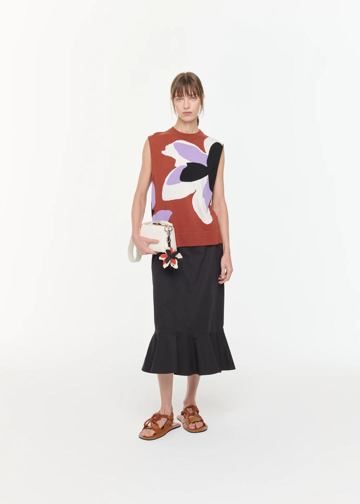 Woman wearing a sleeveless top with abstract design and black skirt on a white background