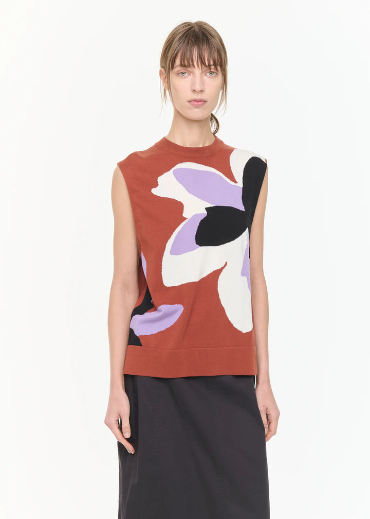 Woman wearing a sleeveless top with abstract floral design on a plain background