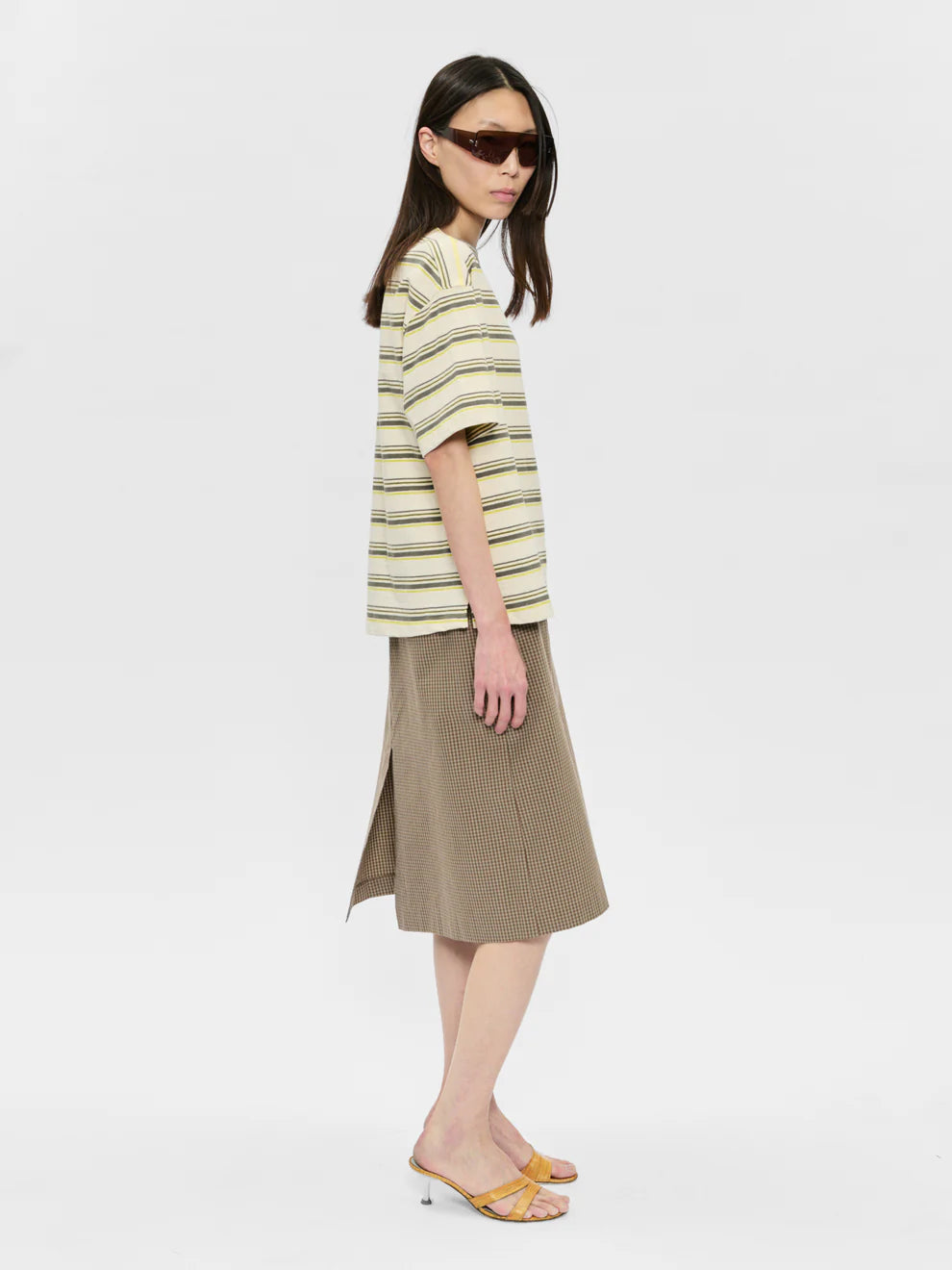Woman wearing a striped shirt and beige skirt on a white background