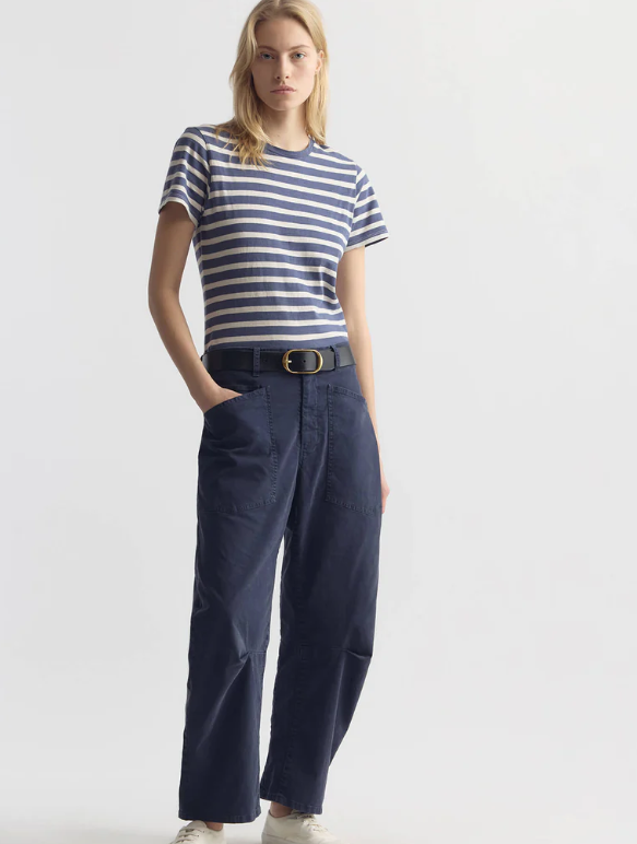 Woman wearing a striped shirt and navy pants on a white background