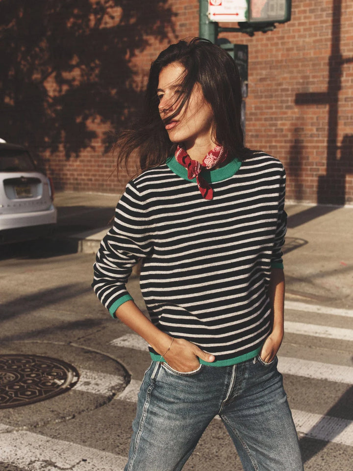 Woman wearing a striped sweater and jeans on a city street.
