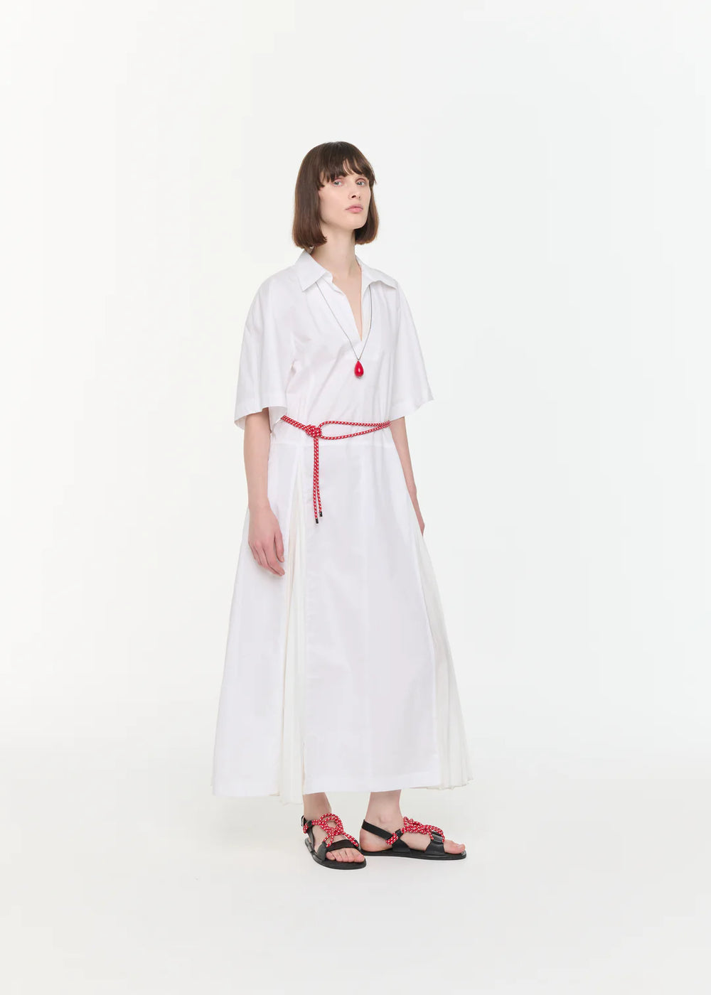 Woman wearing a white dress with a red belt on a white background