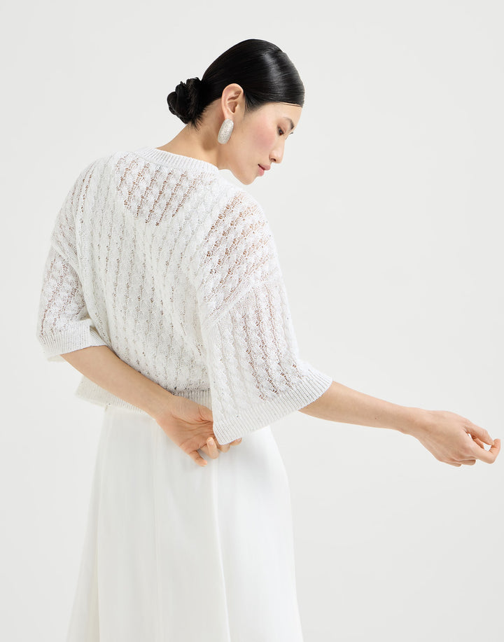 Woman wearing a white knit cardigan over a white dress on a white background