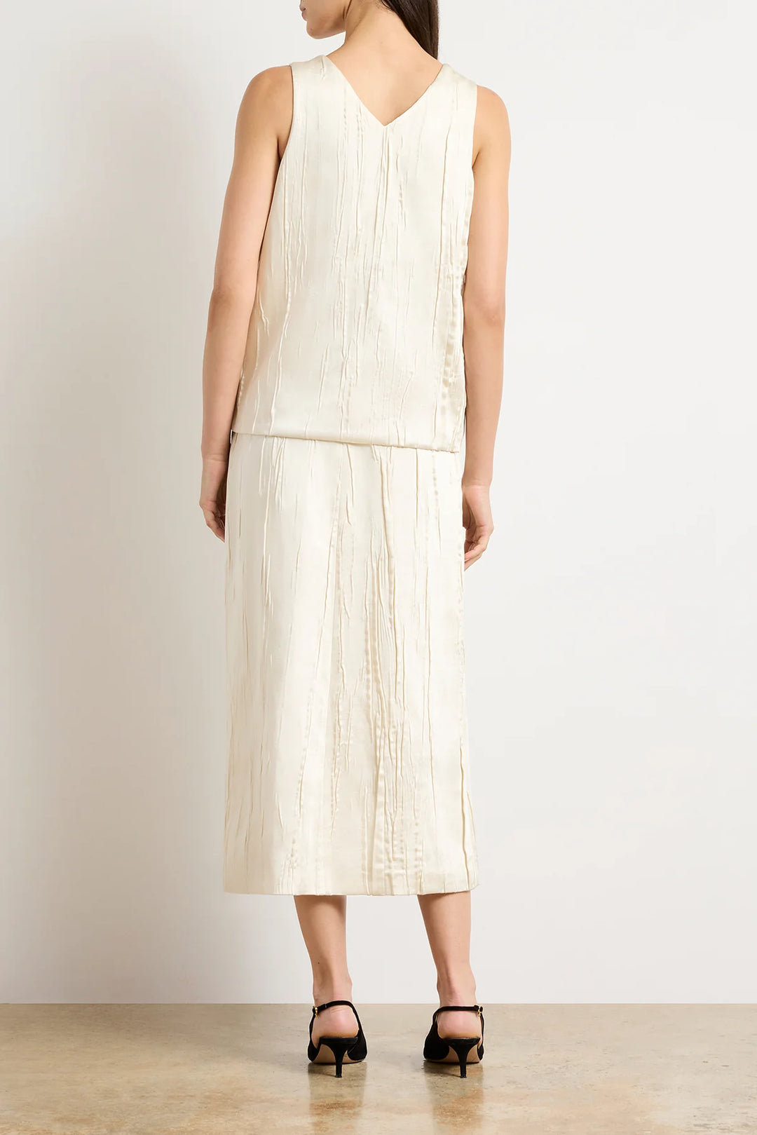 Woman wearing a white pleated dress against a plain background