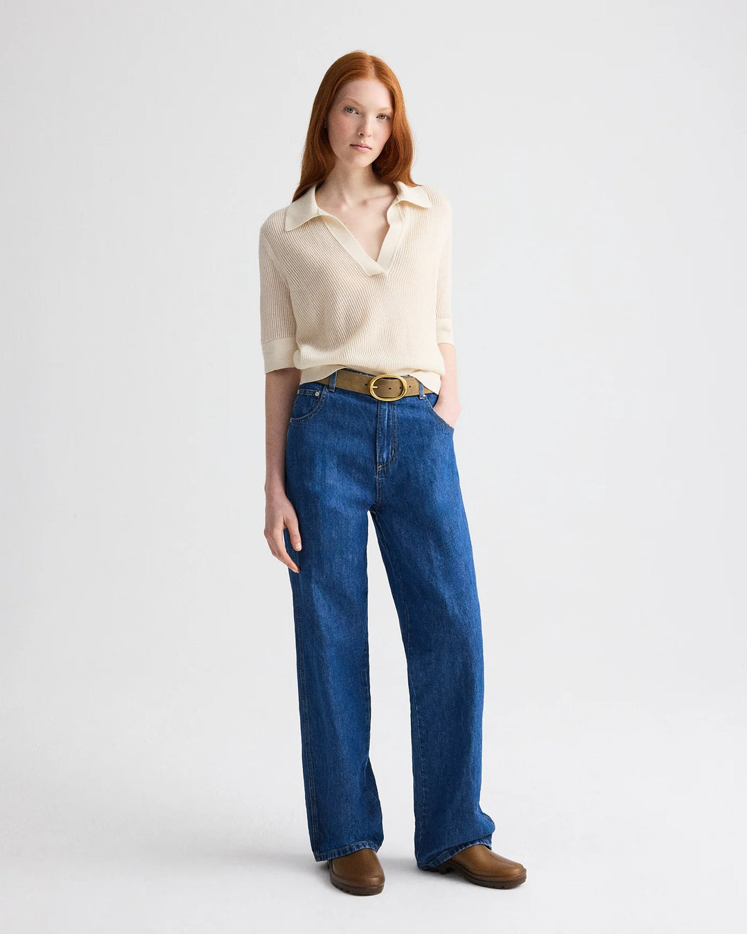 Woman wearing a white shirt and blue jeans on a plain background