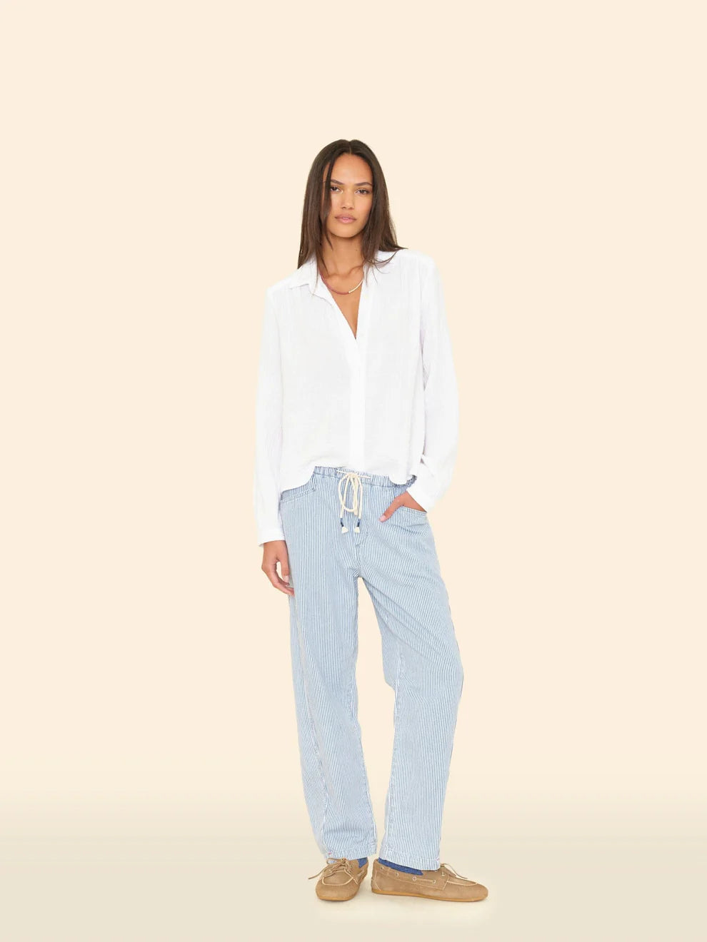 Woman wearing a white shirt and light blue pants on a beige background