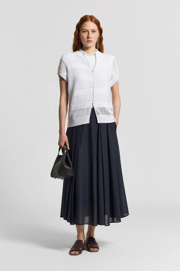 Woman wearing a white short-sleeve top and black skirt holding a black handbag on a light gray background