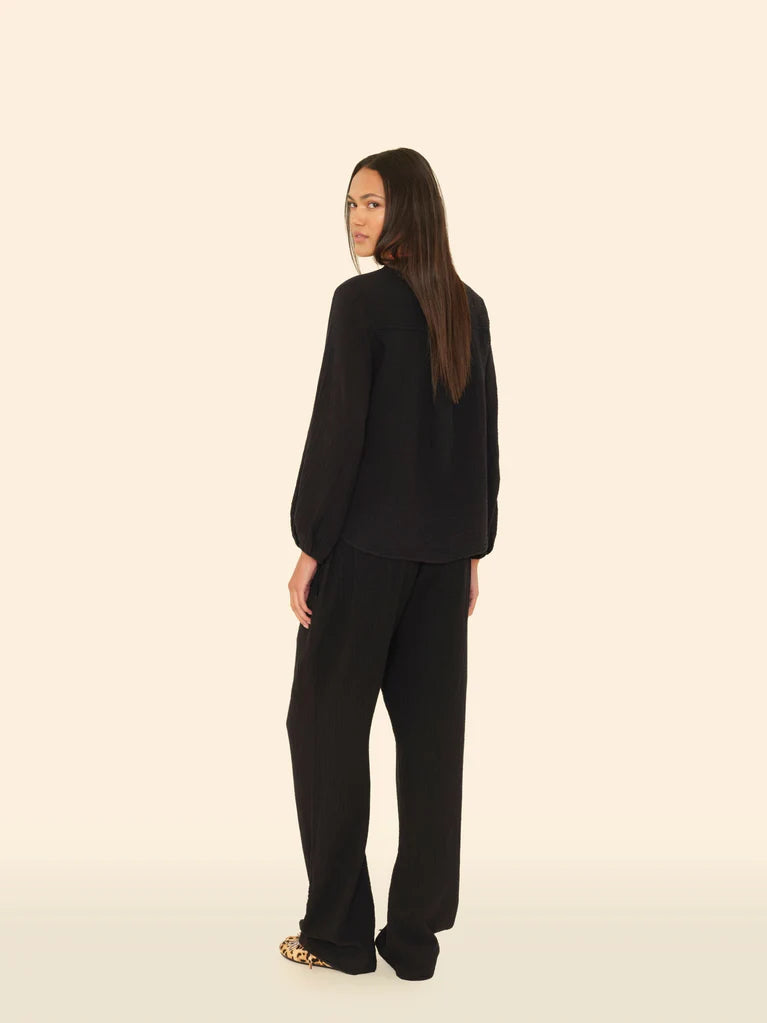 Person wearing a black outfit on a beige background