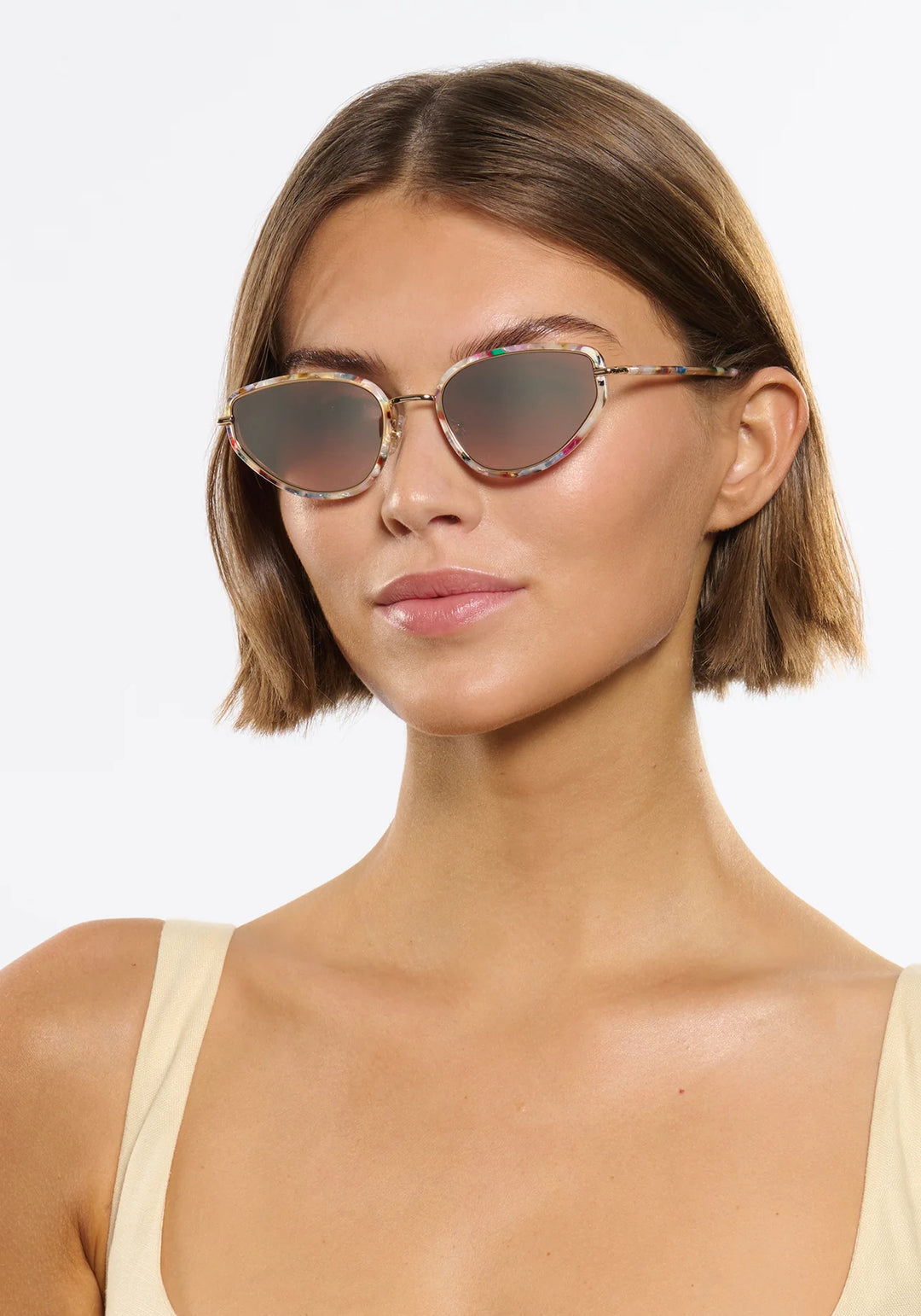 Woman wearing round sunglasses with a neutral background