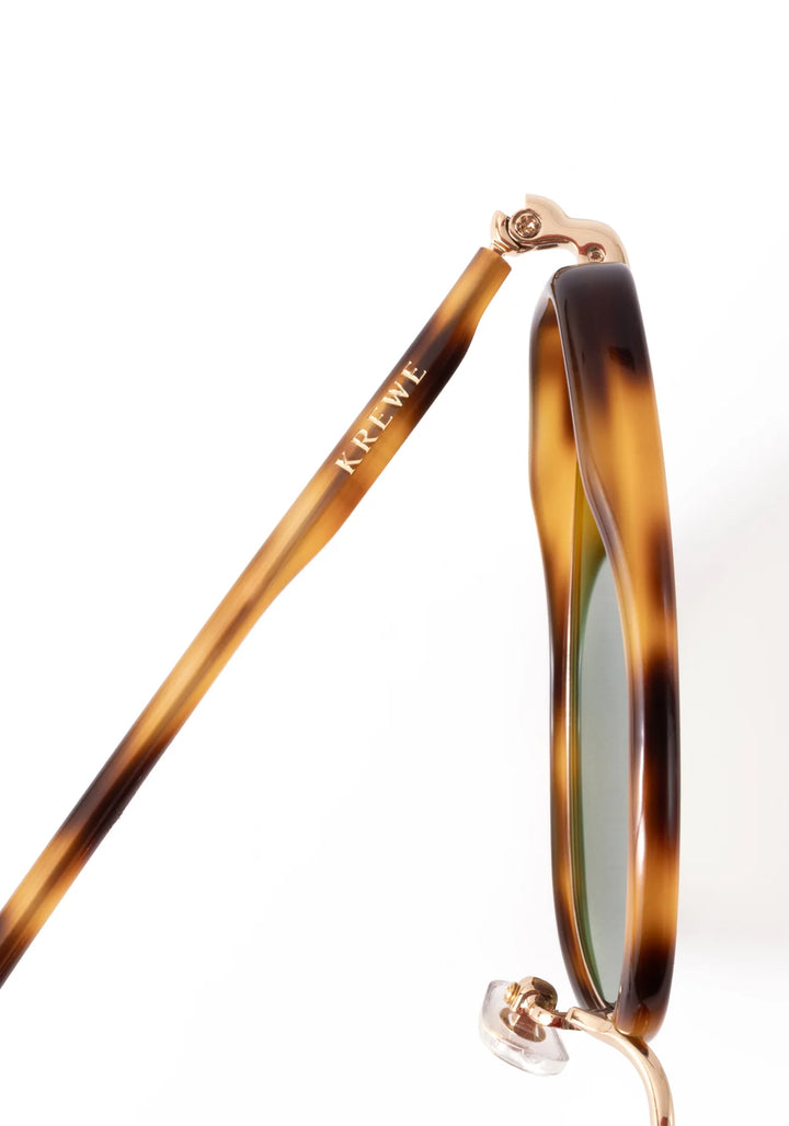 Sunglasses with tortoiseshell frame and green lenses on a white background