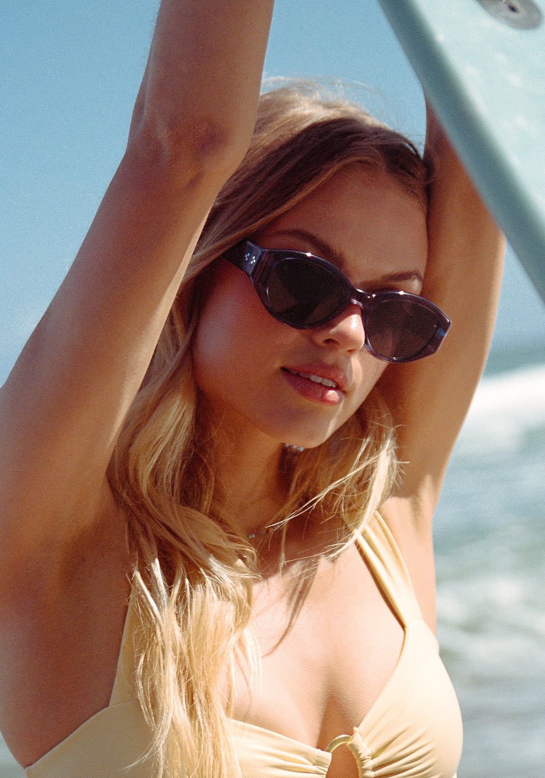 Woman wearing sunglasses and a yellow top with a blurred background