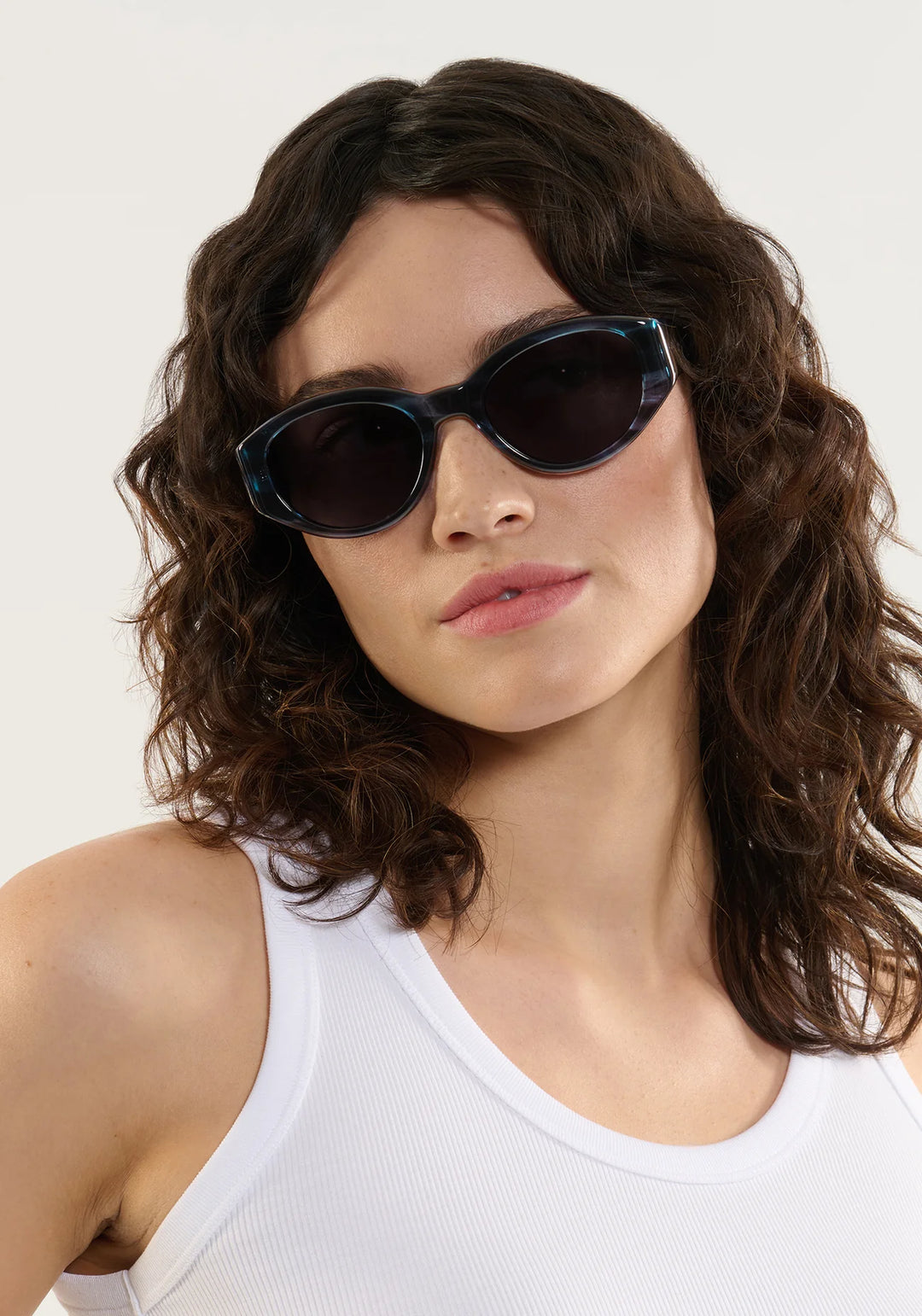 Woman wearing dark sunglasses with a plain background