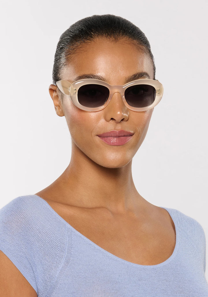 Woman wearing cat-eye sunglasses with a plain background
