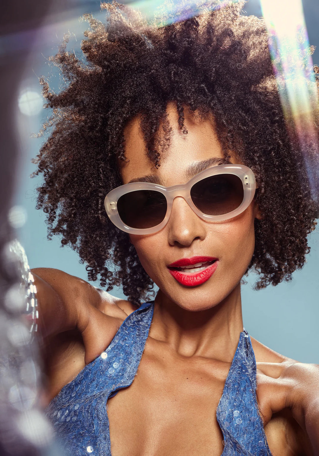 Woman wearing sunglasses and a blue top with a colorful background