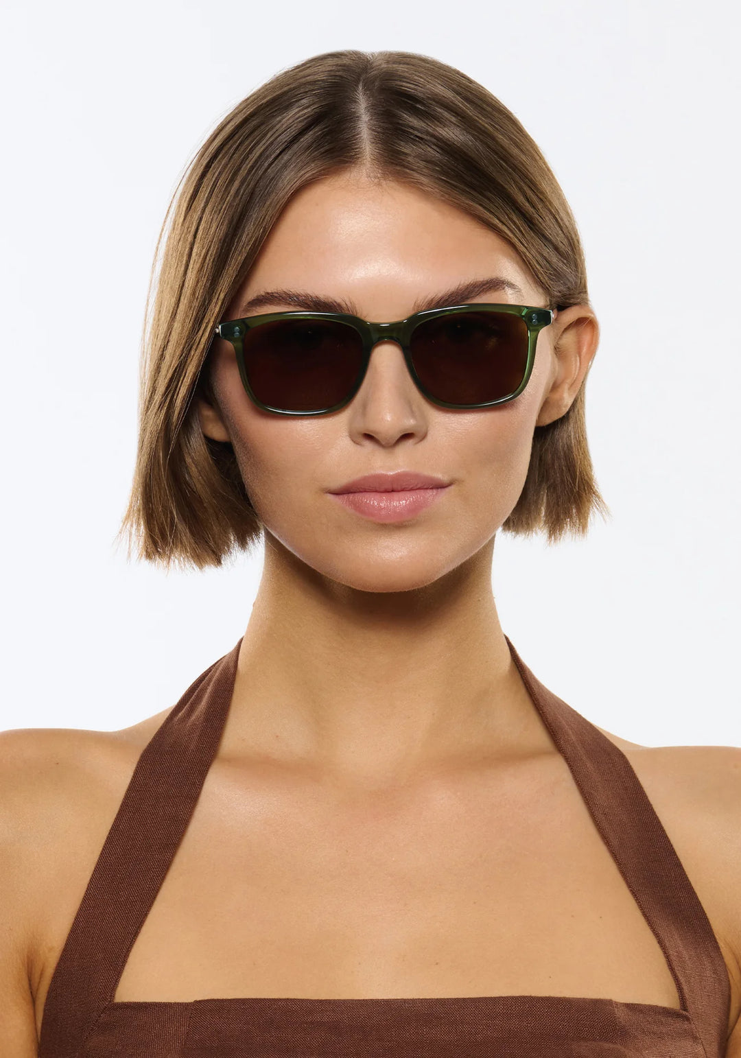 Woman wearing dark sunglasses against a plain background