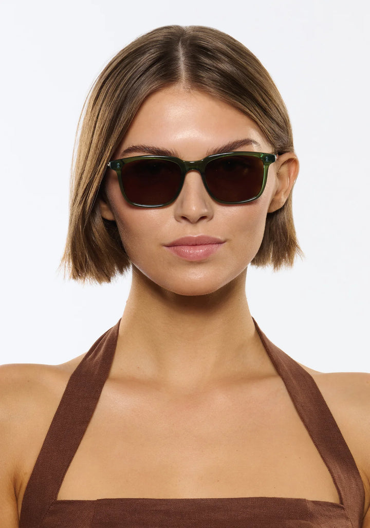 Woman wearing dark sunglasses against a plain background