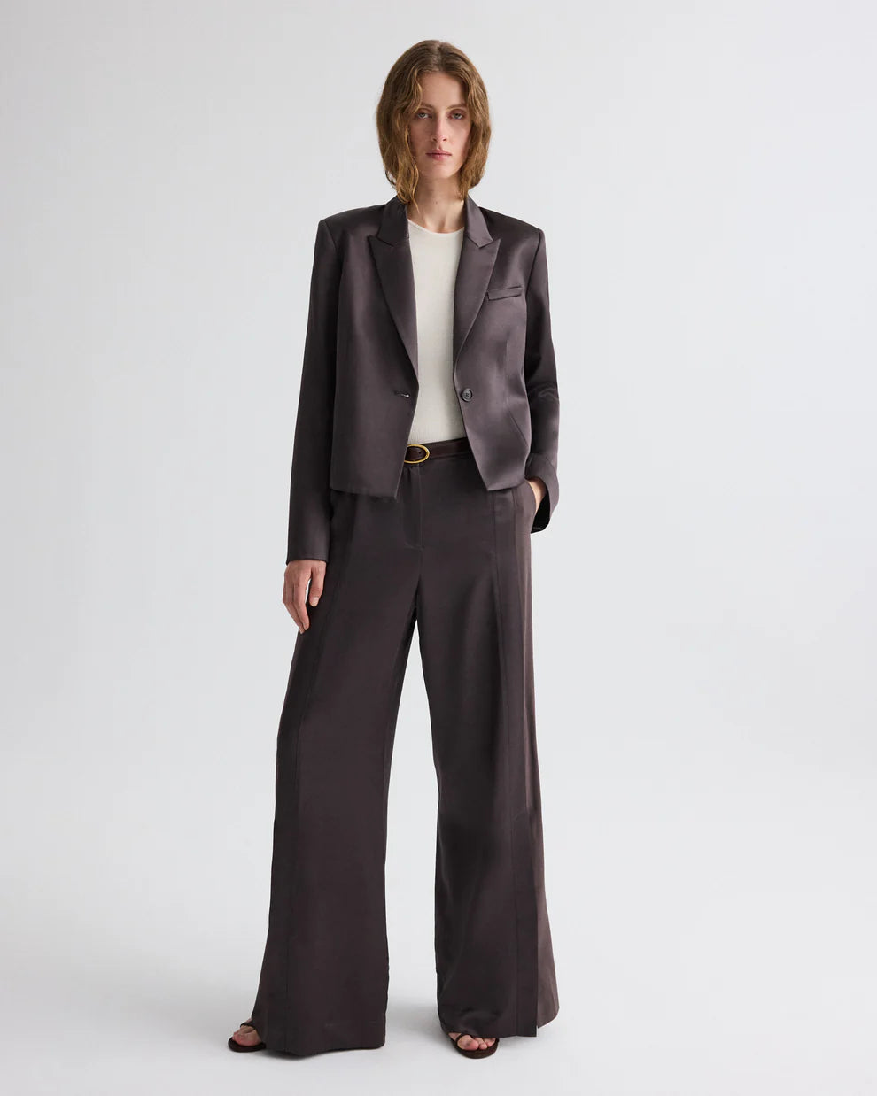 Woman wearing a dark brown suit with a white shirt on a white background