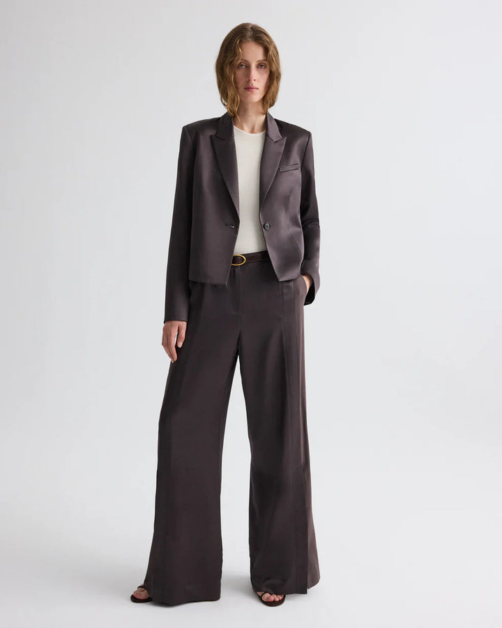 Woman wearing a dark brown suit with a white shirt on a white background