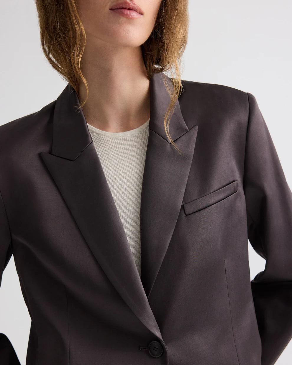 Dark gray blazer worn by a person on a light gray background