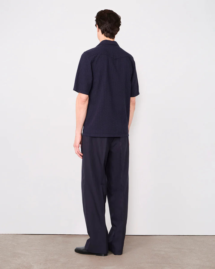 Person wearing a navy blue outfit against a white wall