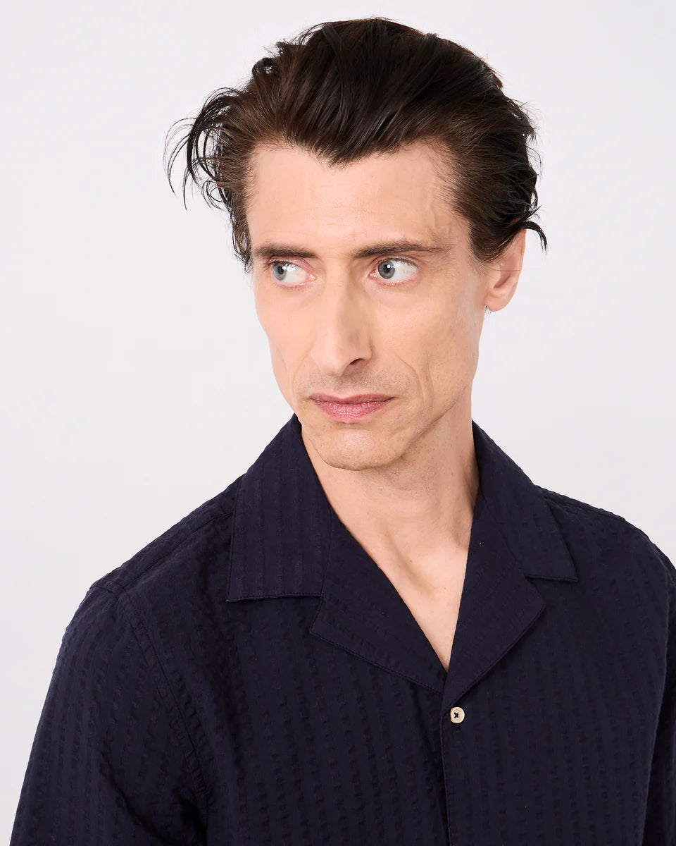 Man wearing a dark blue shirt against a white background