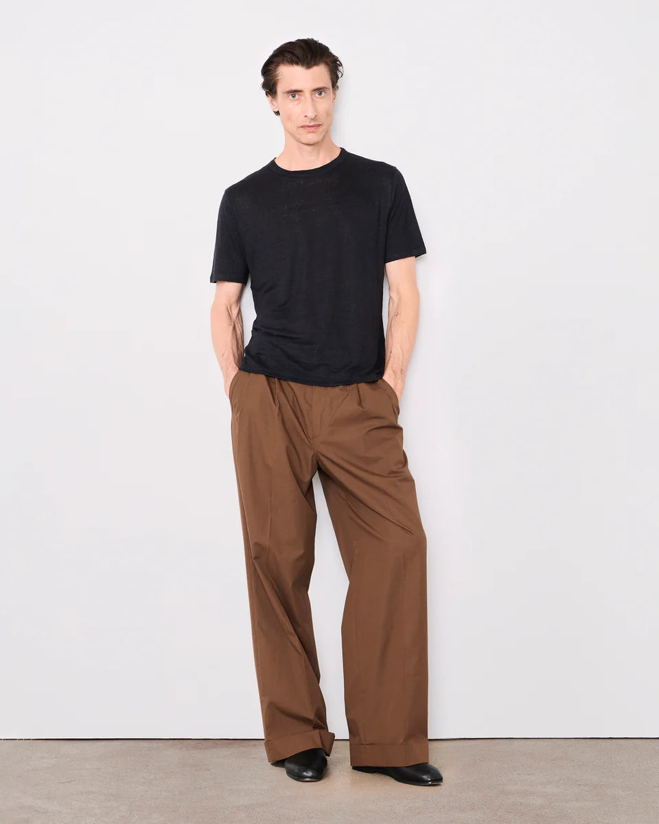 Man wearing a black t-shirt and brown pants against a white background