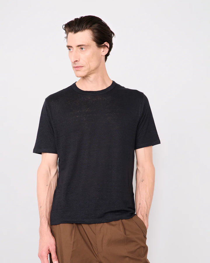 Man wearing a black t-shirt and brown pants against a white background