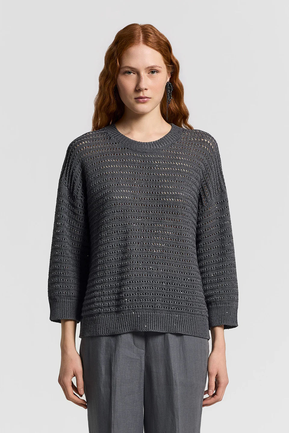 Woman wearing a gray textured sweater and pants on a light gray background