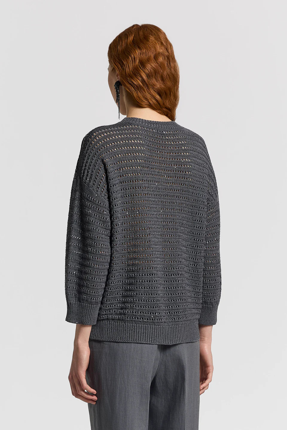 Person wearing a gray textured sweater on a light gray background