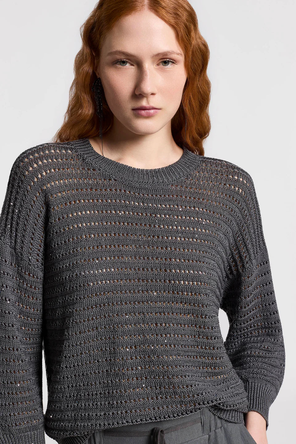 Woman wearing a textured gray sweater against a plain background