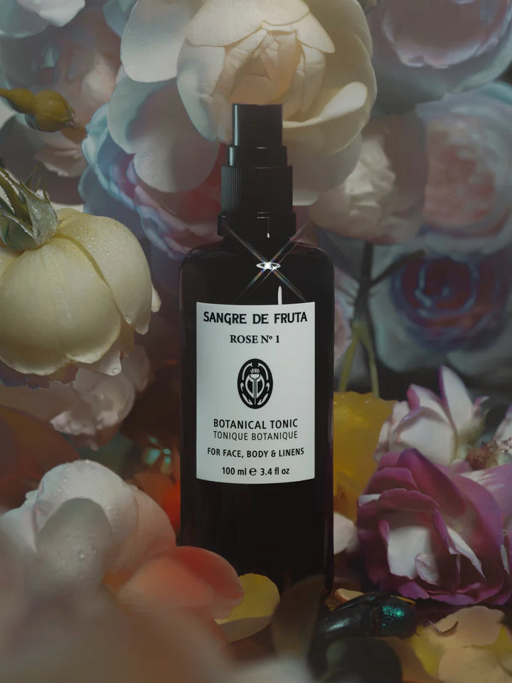 Bottle of Sangre de Fruta Botanical Tonic with flowers in the background