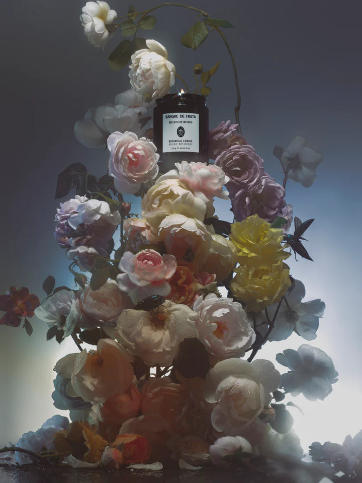 Floral arrangement with a black bottle labeled 'Santoma de Praga' against a gradient background
