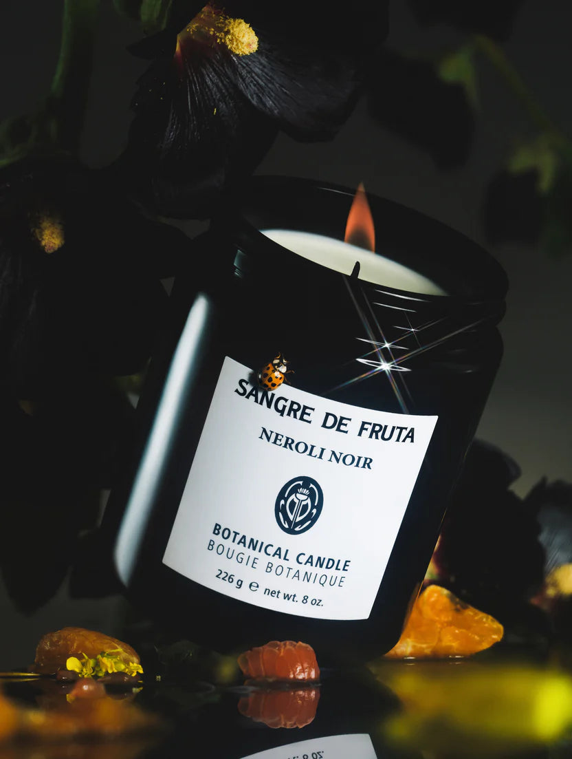 Sangre de Fruta Neroli Noir candle with a label on a dark background