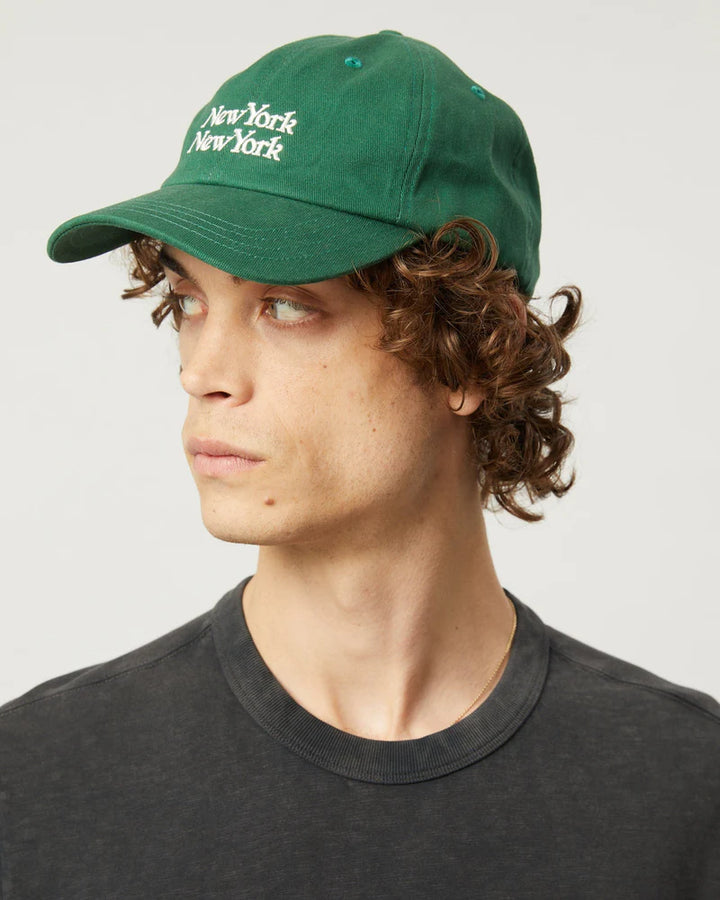 Person wearing a green cap with 'New York' text on a plain background