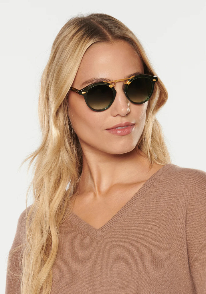 Woman wearing round sunglasses with a plain background