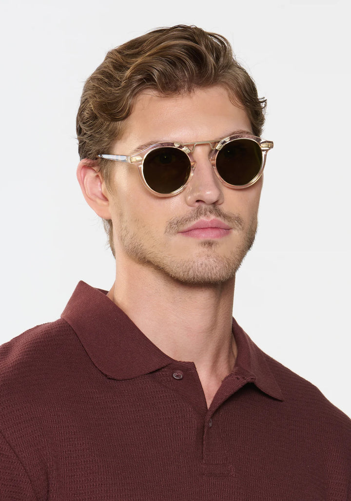 Man wearing round sunglasses with a plain background