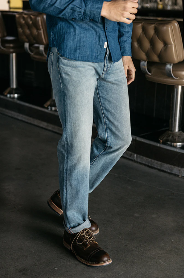 Person wearing blue jeans and brown shoes in a bar setting
