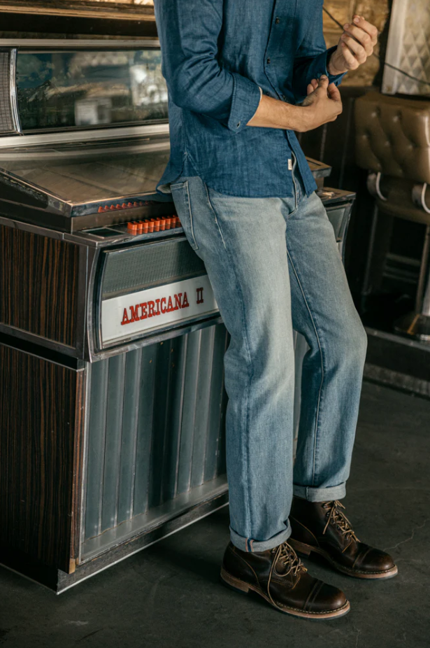 Person wearing a denim jacket and jeans standing next to an Americana II jukebox.