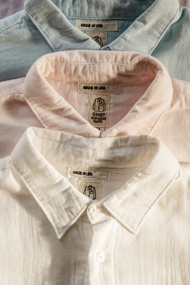 Close-up of three shirts with visible labels on a light background