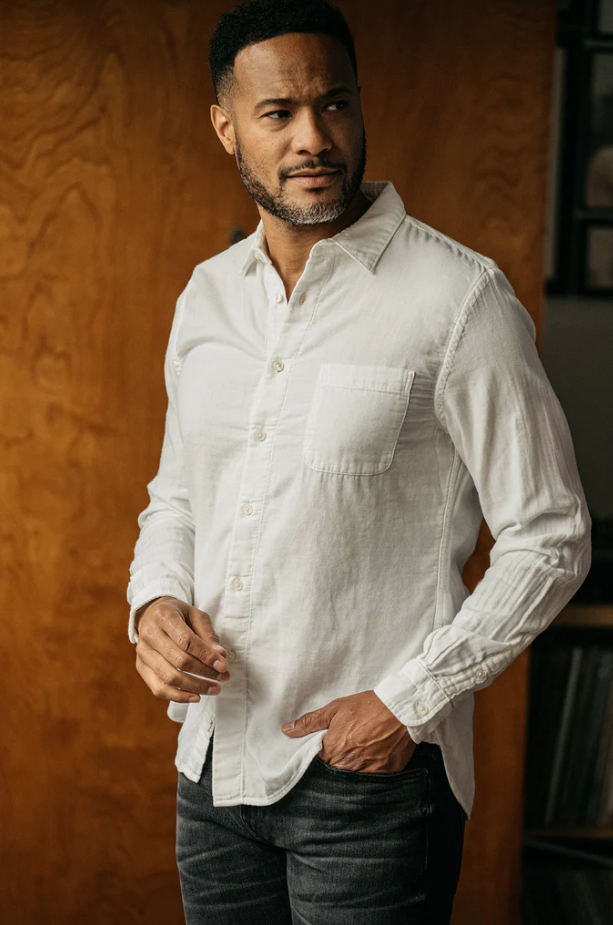 Man wearing a white button-up shirt against a wooden background