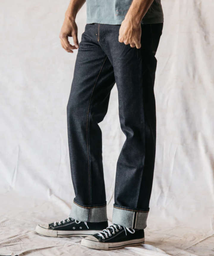 Person wearing dark jeans and black sneakers on a plain background
