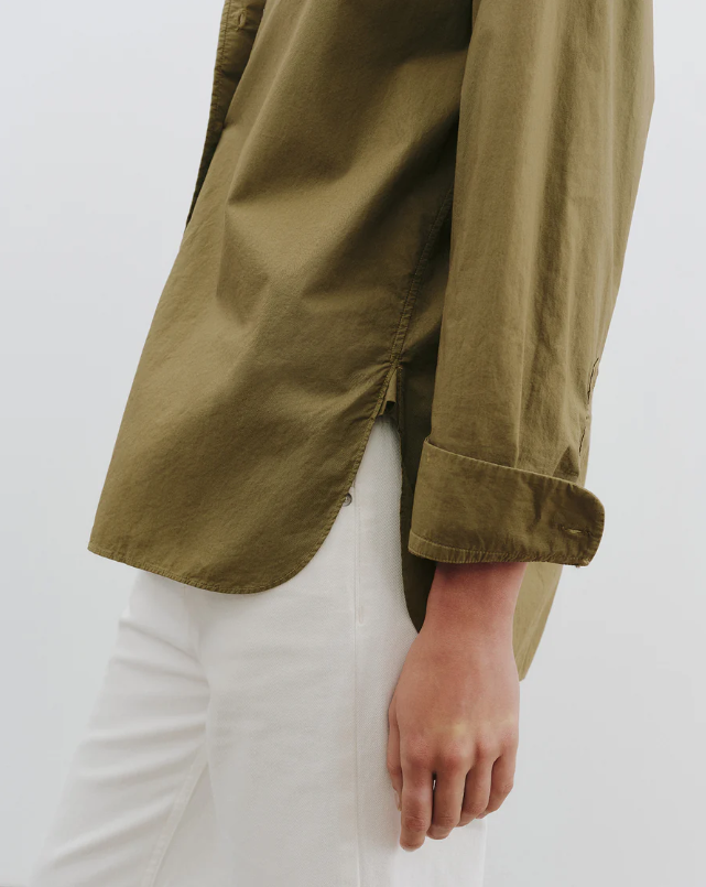 Green shirt with rolled-up sleeves worn by a person on a white background