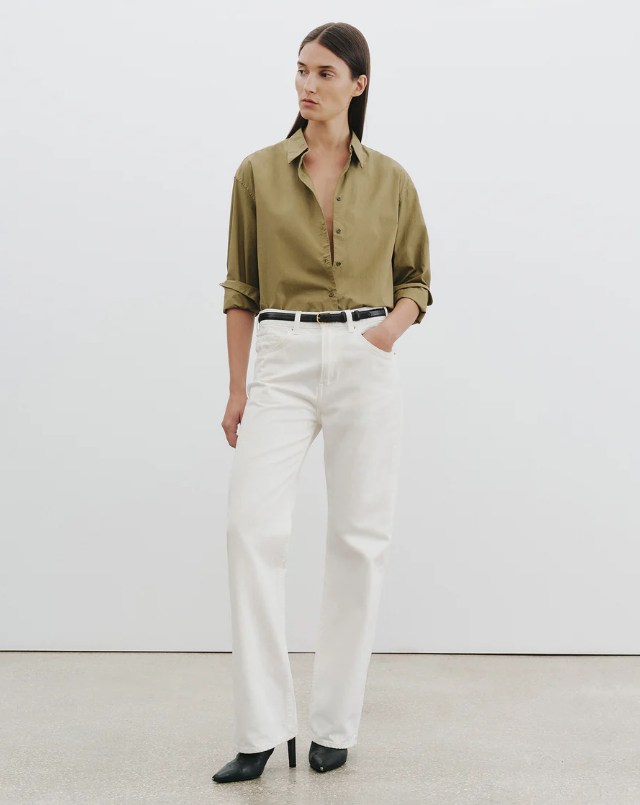 Woman wearing a green shirt and white pants against a white background