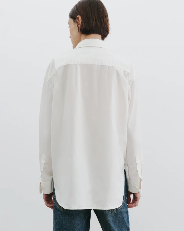 Person wearing a light-colored shirt with a white background