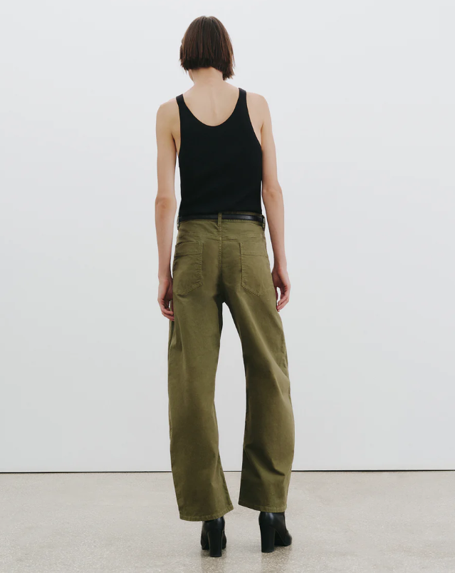 Person wearing a black tank top and olive green pants on a white background