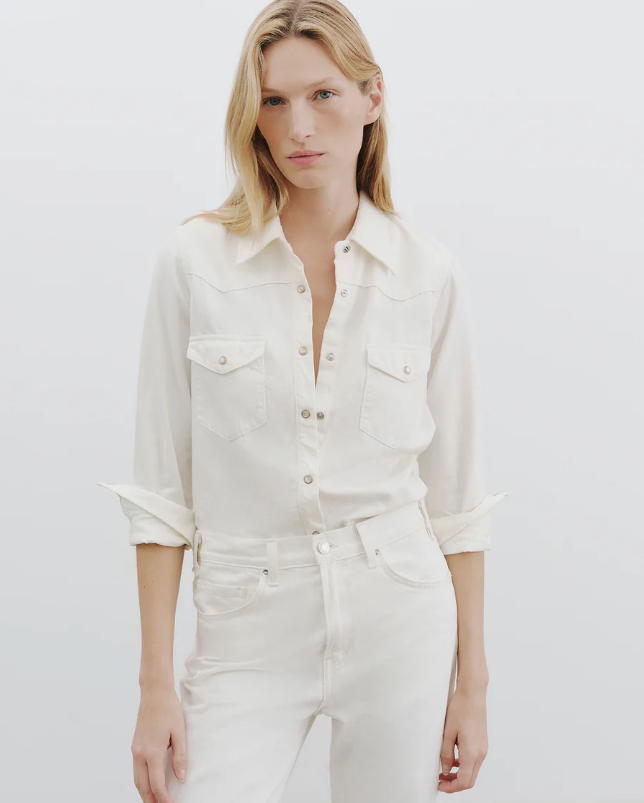 Woman wearing a white denim shirt and pants on a plain background